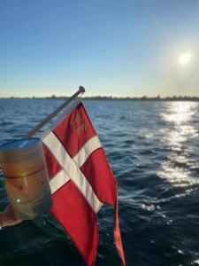 urne og det danske flag bag på båd